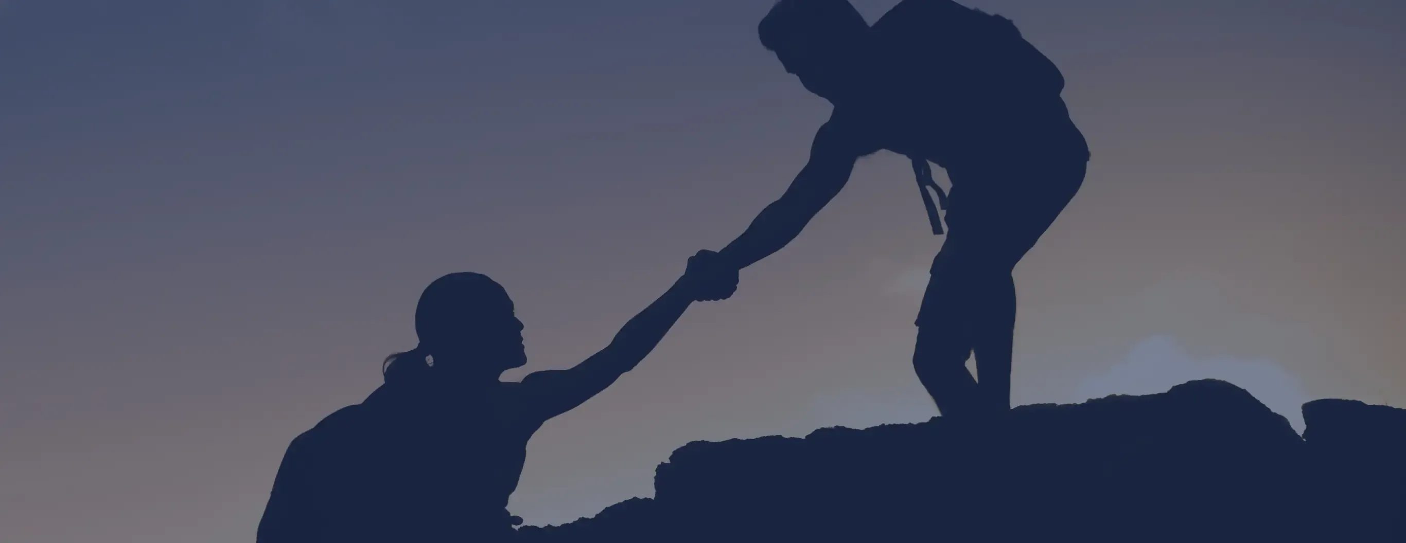 Two individuals holding hands, standing together on a mountain peak